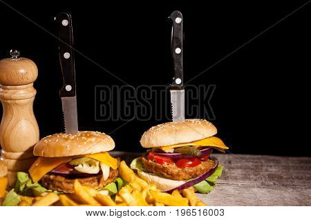 Fast food of tasty delicious burgers on wooden background next to fries. Unhealthy snack