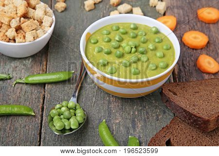 Green Peas Soup In Bowl With Rusks On Wooden Table