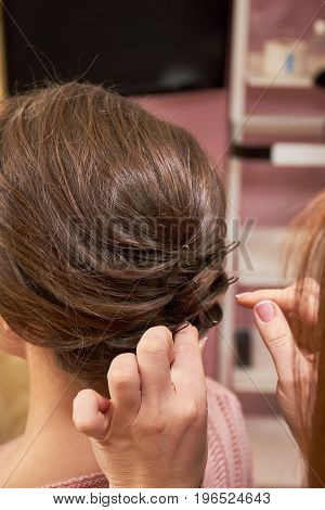 Hands of hairdresser working. Female hair with bobby pins.