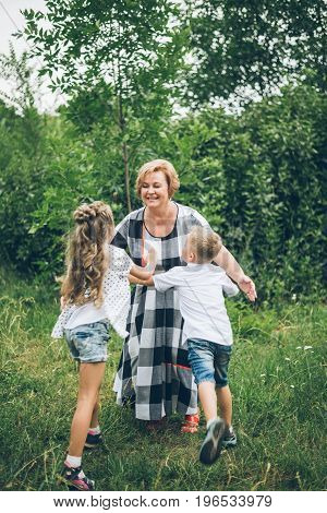 Grandmother playing in the park with grandchildren, siter with brother