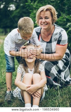 Grandmother playing in the park with grandchildren, siter with brother