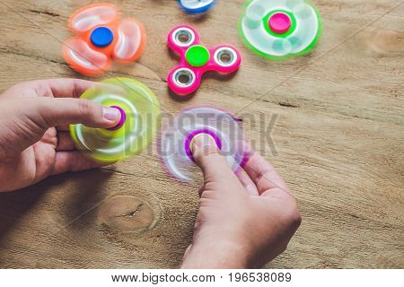 A Man Hand Holding Hand Spinner Or Fidget Spinner Over Wooden Background