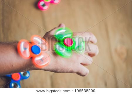 A Man Hand Holding Hand Spinner Or Fidget Spinner Over Wooden Background