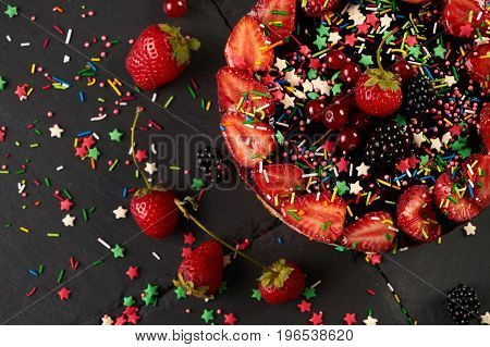 Fresh fruit and berry tart dessert dark stone background. Delicious sweet cake with raspberries strawberries blackcherry and cream. View from above