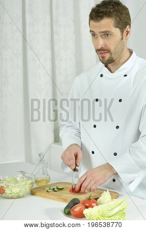 Portrait of a handsome young chief preparing vegetable salad