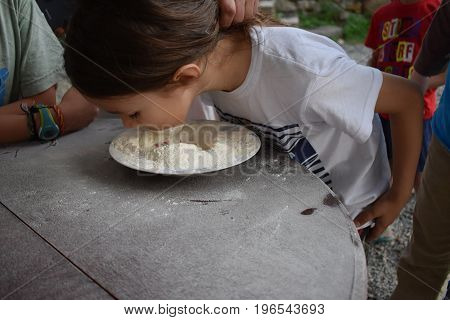 Child plays fetch a prize in a bowl of flour