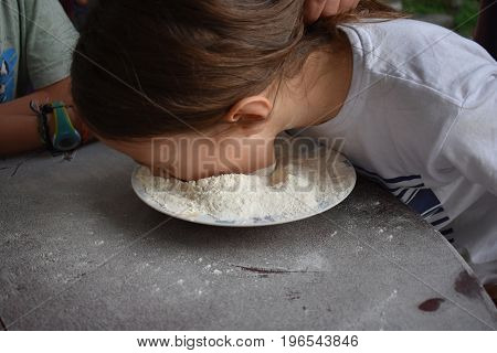 Child plays fetch a prize in a bowl of flour
