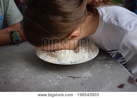Child plays fetch a prize in a bowl of flour