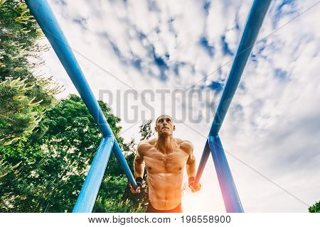 Man doing push ups on parallel bars in a park