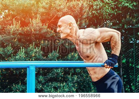 Man doing push ups on parallel bars in a park