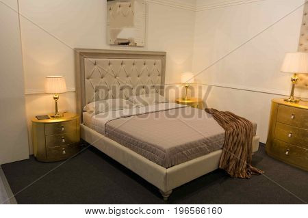 White bed with lamps at the edges with a leather headboard