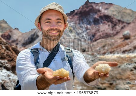 A smiling traveler holds out to the camera the palms on which large pieces of rock salt lie Hormuz Island Hormozgan Province southern Iran.