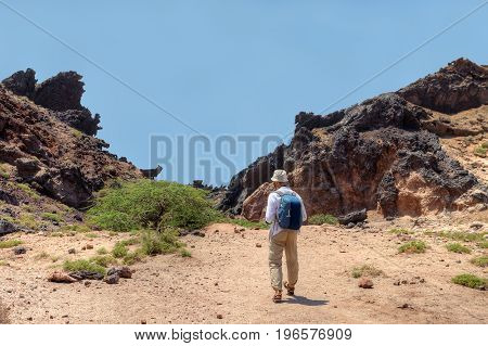 View from the back to the tourist with a backpack which makes a walk on the picturesque places. Hormuz Island Hormozgan Province southern Iran.