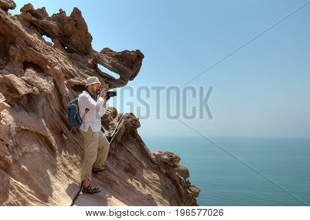Photographer traveler stands on rock in Hormoz Island southern Iran.