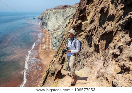 A happy tourist with a camera stands on the edge of a cliff Hormuz Island Hormozgan Province southern Iran.