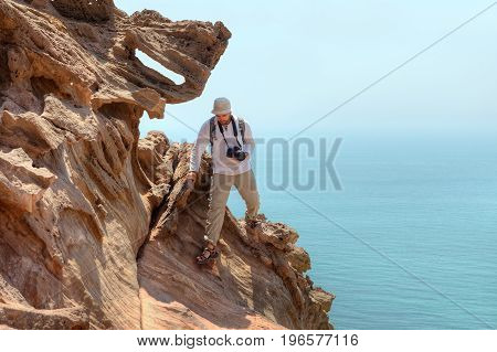 Photographer traveler climbs the cliff above the sea Hormuz Island Hormozgan Province Iran.