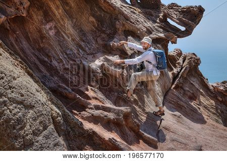 A traveler photographer climbs on a rock to photograph a beautiful natural view Hormuz Island Hormozgan Province Southern Iran.