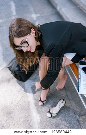 Confident and uninhibited girl taking off shoes. Young woman with tired legs, modern social behavior
