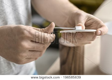 Guy is using a wrench on the round metal white detail in the workshop. On the table there are wooden and white metal cylindrical billets. Closeup low apeture photo. Horizontal.