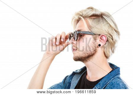 Men fashion accessories hairstyle modeling concept. Artistic hipster blonde man wearing and holding sunglasses profile portrait studio shot isolated