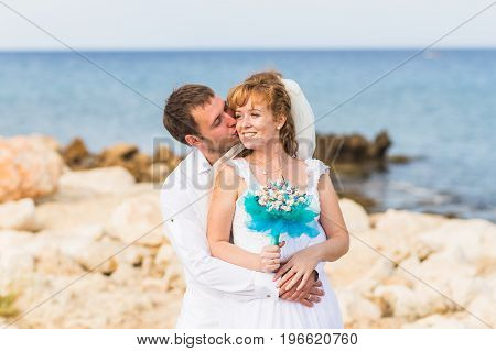 Bride and groom on a romantic moment near the sea.