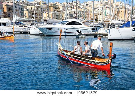 VITTORIOSA, MALTA - MARCH 31, 2017 - Passengers on board a traditional Maltese Dghajsa water taxi in the harbour with views towards Senglea waterfront Vittoriosa Malta Europe, March 31, 2017.
