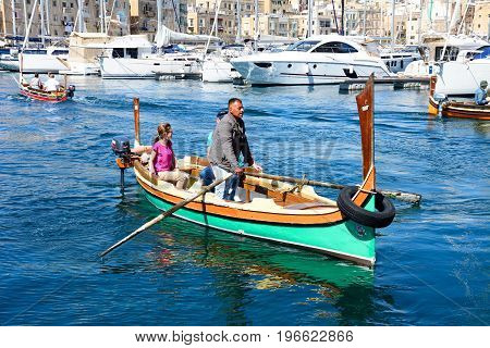VITTORIOSA, MALTA - MARCH 31, 2017 - Passengers on board traditional Maltese Dghajsa water taxis in the harbour with views towards Senglea waterfront Vittoriosa Malta Europe, March 31, 2017.
