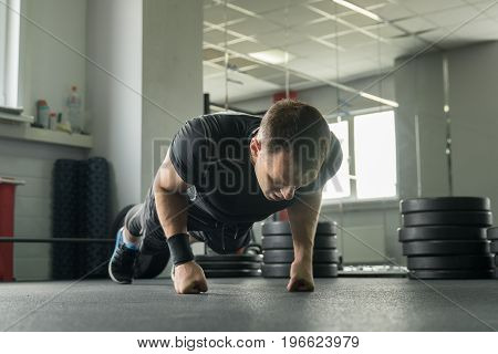 Sportsman Wearing Black Shorts And T-shirt Doing Push-ups On Fists In Gym.