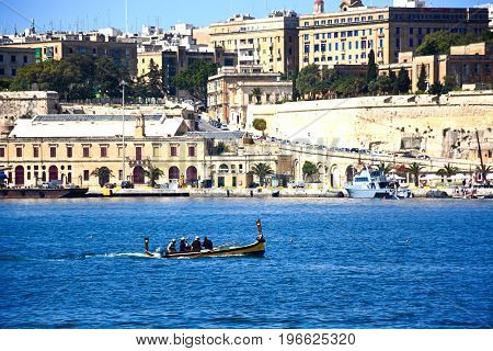 VALLETTA, MALTA - MARCH 31, 2017 - Passengers on board a traditional Maltese Dghajsa water taxi in the grand harbour with views towards Valletta Vittoriosa Malta Europe, March 31, 2017.