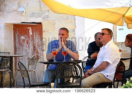 VITTORIOSA, MALTA - MARCH 31, 2017 - Tourists relaxing at a pavement cafe along the waterfront Vittoriosa Malta Europe, March 3, 2017.