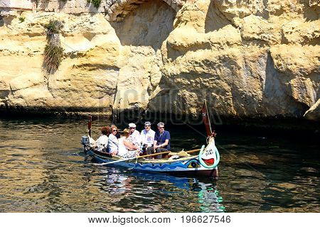 VITTORIOSA, MALTA - MARCH 31, 2017 - Passengers on board a traditional Maltese Dghajsa water taxi in an inlet alongside Fort San Angelo Vittoriosa Malta Europe, March 31, 2017.