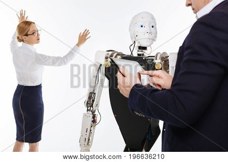 Computer mind. Energetic remarkable brilliant scientists using innovative technologies while programming the robot and running a number of tests