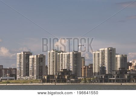 Sportive airplane flying over modern city, telephoto