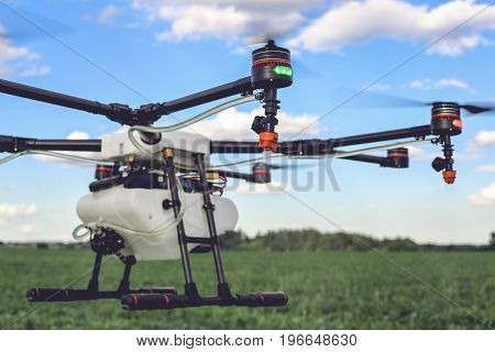 Closeup view of flying professional drone quadrocopter at the green field.