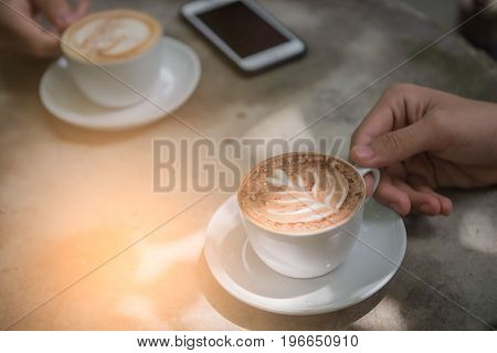 Cup coffee and phone on the table in coffee shop at morning  .