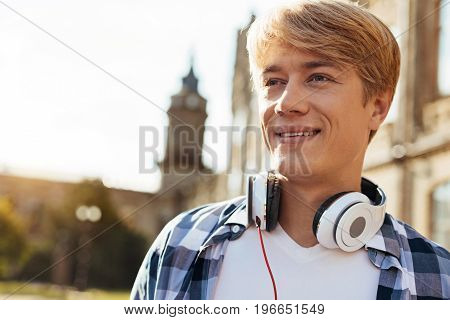 Inspired kid. Productive quick witted handsome guy attending university and heading for another lecture while taking a look at the campus