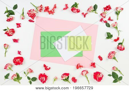 Flowers composition. Frame made of rose flowers and colorful envelopes in the middle. Flat lay, top view