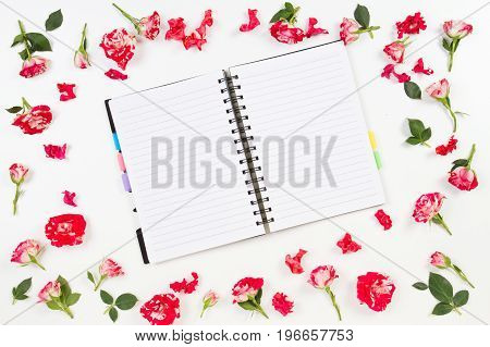 Flowers composition. Frame made of rose flowers. Open paper notebook or diary in the middle. Flat lay, top view