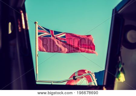The uk red ensign the british maritime flag flown from yacht sail boat blue sky and baltic sea. Summer and travel voyage