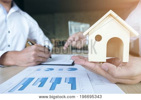Man sign a home insurance policy on home loans Agent holds home and pointing loan documents. Real Estate concept.