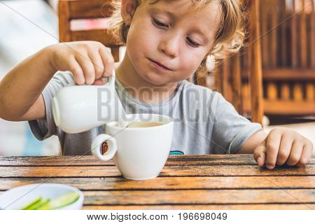 Happy Nice Boy Pours Honey Into The Tea In Summer Green Garden. Portrait. Outdoor