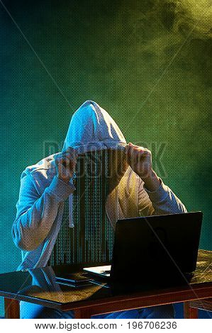 Hooded computer hacker stealing information with laptop. Concept of threat