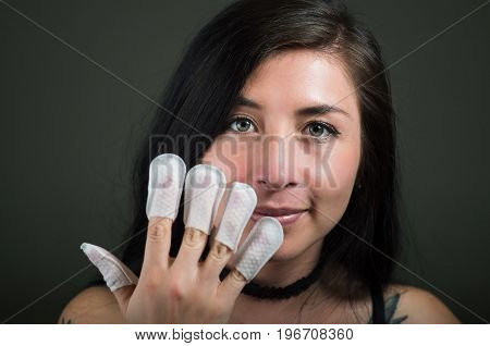 Portrait of young woman wearing nails protector in her nails, hand and ideal clean manicure, in a black background.