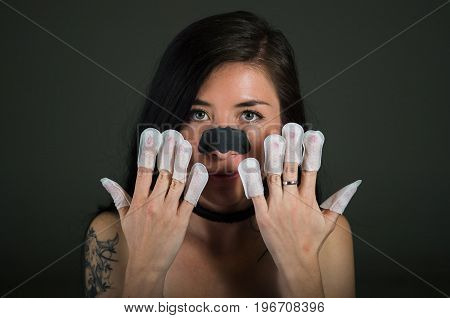 Portrait of young woman wearing nails protector in her nails, hand and ideal clean manicure, in a black background.