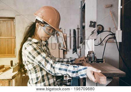 Asian pretty female carpenter using Electric Sander for wood.