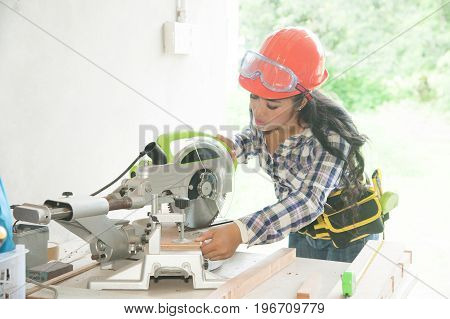 Asian pretty female carpenter using Electric Sander for wood.