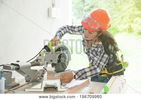 Asian pretty female carpenter using Electric Sander for wood.