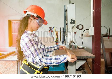 Asian pretty female carpenter using Electric Sander for wood.