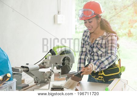 Pretty Asian carpenter woman is marking on wood for cut.