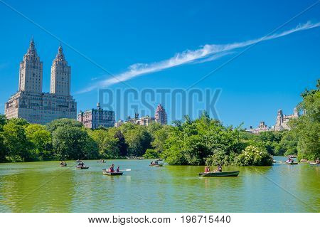 NEW YORK, USA - NOVEMBER 22, 2016: Unidentified group of people paddling in the Lake in Central Park in a beautiful sunny day, with a huge buildings behind in New York.